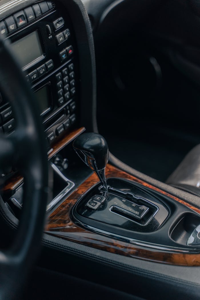 Close-up of a vintage car's interior featuring a classic gear shift lever and wooden dashboard trim.